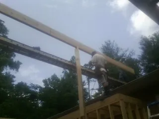 Carpenter setting a ridge beam over a new addition frame — Ice Dam Removal by Roofing Brothers in Wynot