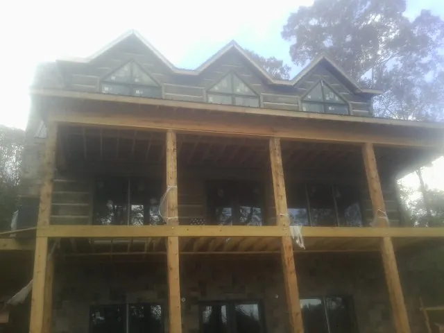 Dormers and porch framing on a large log home under construction — Roof Coating work by our crew in Wynot