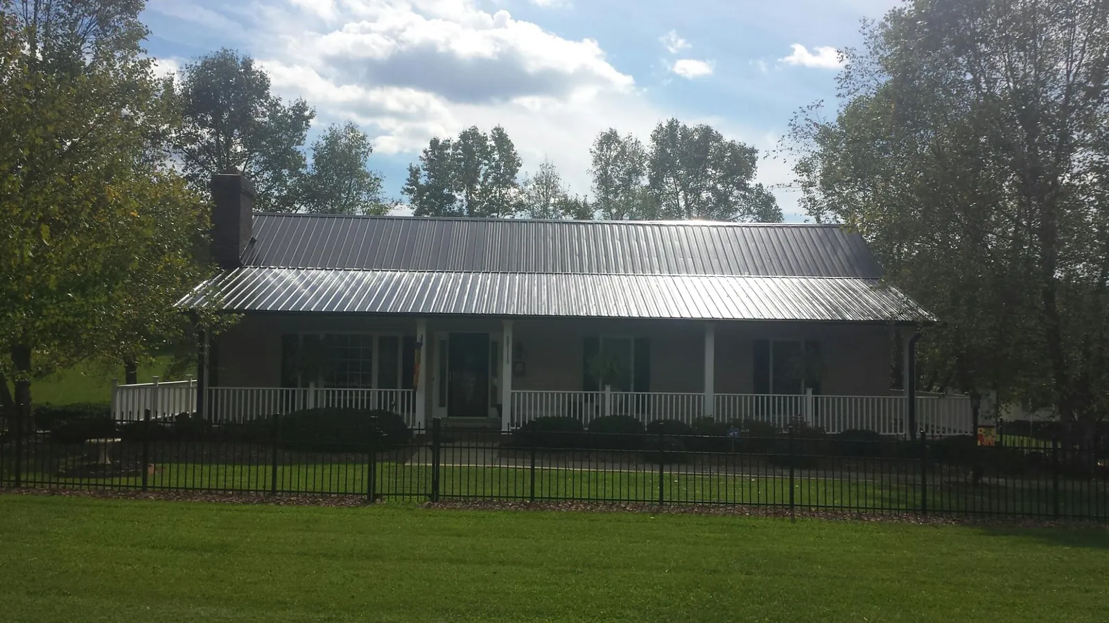 Gray metal roof on a brick ranch with a full width front porch — Gutter Guard Installation work by our crew in Wynot