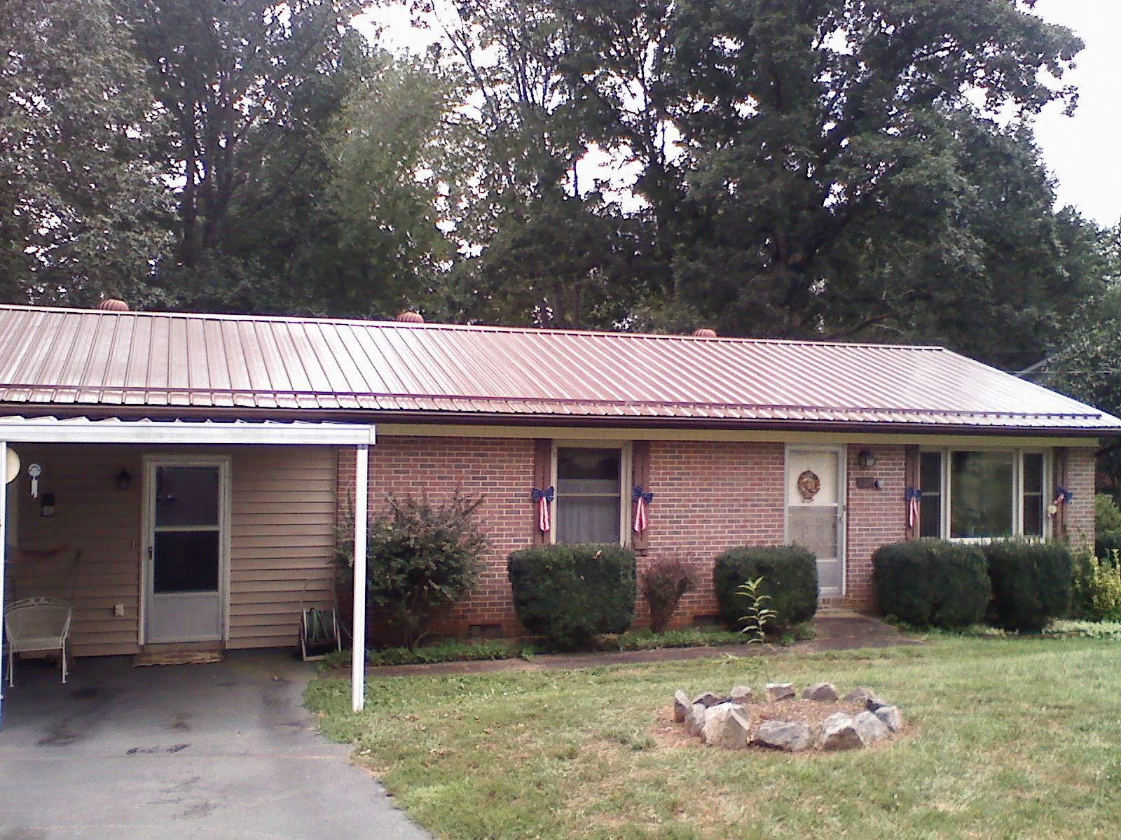 Bronze metal roof and carport on a brick ranch home — Roof Repair work by our crew in Wynot