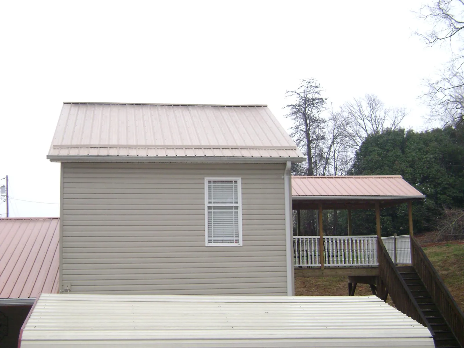Tan metal roofs on a two story addition and attached porch, from a Roof Replacement job in Wynot